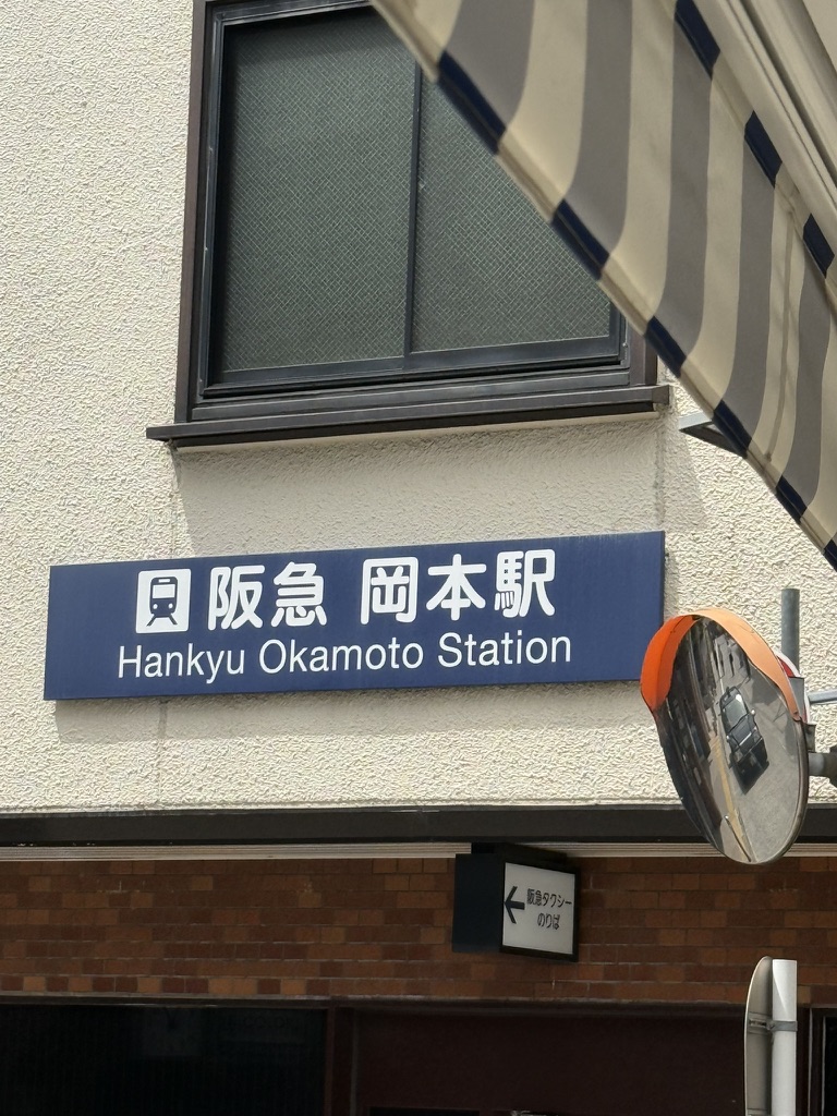 Hankyu Okamoto Station sign on the station building.