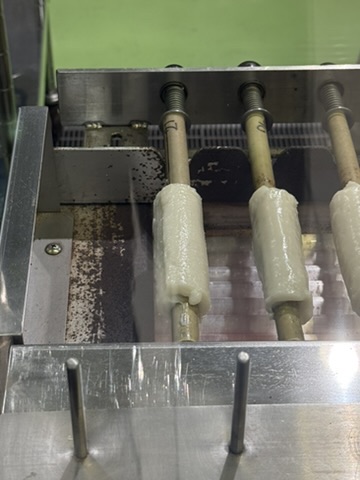 Chikuwa being formed on bamboo sticks at Yamasa Kamaboko.